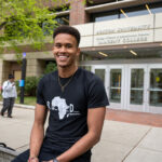 Photo: A picture of a man smiling and posing in front of a Boston University building